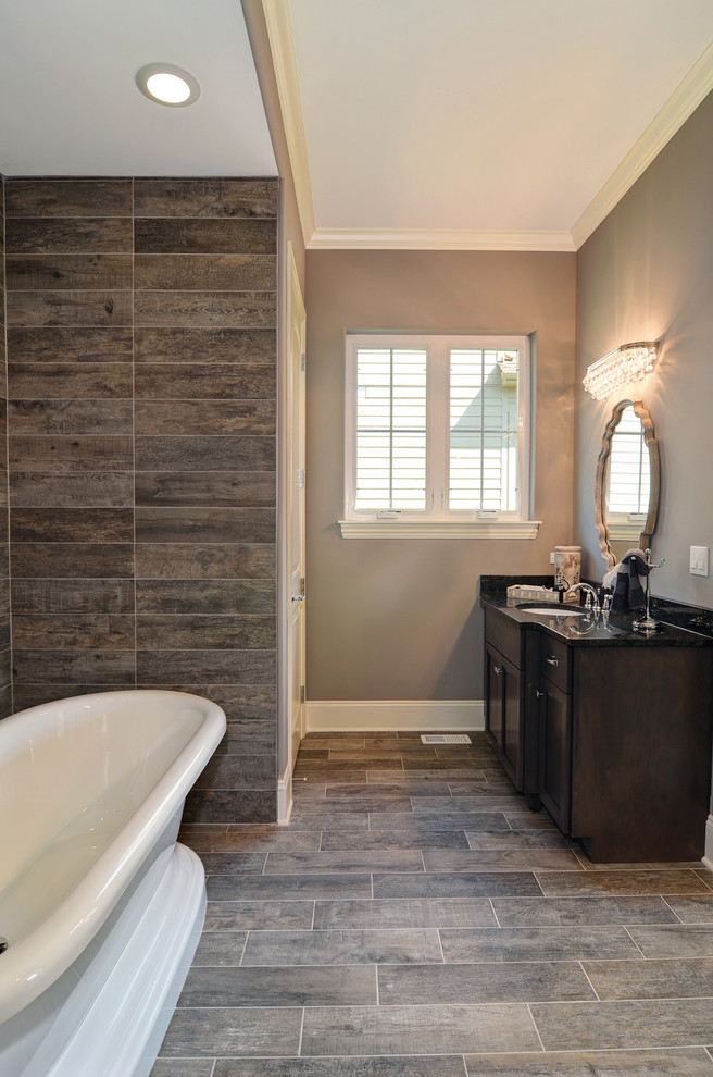 Design ideas for a mid-sized transitional master bathroom in Chicago with recessed-panel cabinets, dark wood cabinets, a freestanding tub, a corner shower, brown tile, ceramic tile, grey walls, dark hardwood floors, an undermount sink, granite benchtops, brown floor and a hinged shower door.