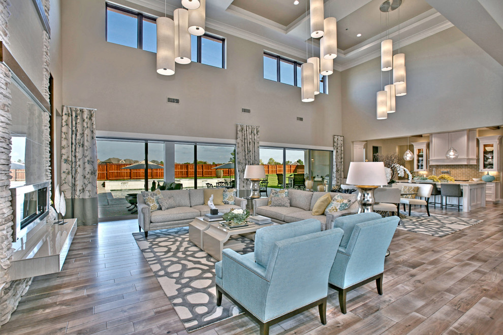 Large transitional open concept light wood floor living room photo in Dallas with beige walls, a standard fireplace, a tile fireplace and a wall-mounted tv