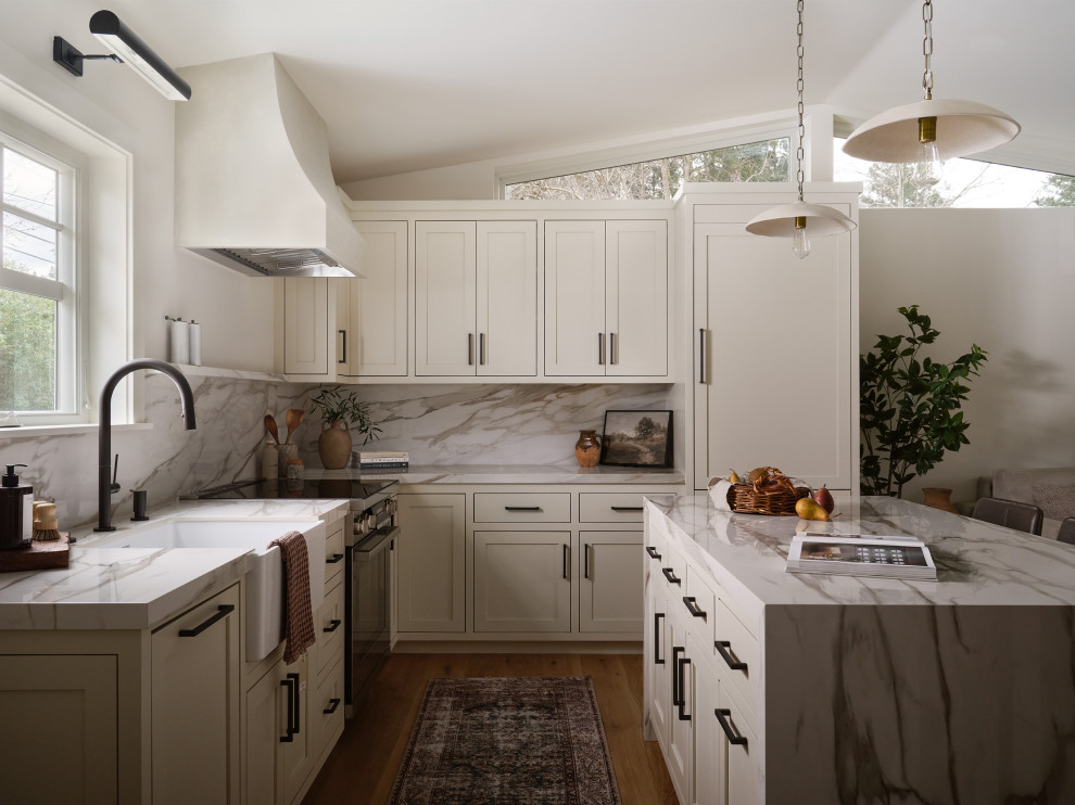 Transitional l-shaped medium tone wood floor, brown floor and vaulted ceiling kitchen photo in San Francisco with a farmhouse sink, shaker cabinets, beige cabinets, stainless steel appliances, an island and gray countertops