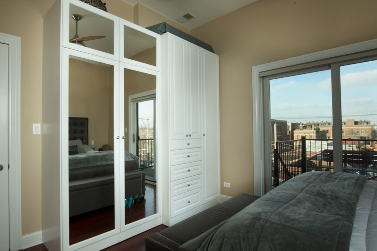 Inspiration for a mid-sized transitional women's built-in wardrobe in Chicago with raised-panel cabinets, white cabinets and dark hardwood floors.