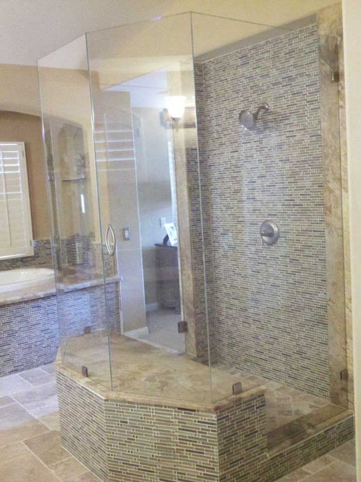 This is an example of a large transitional master bathroom in Orange County with a drop-in tub, an alcove shower, beige tile, multi-coloured tile, matchstick tile, beige walls, travertine floors, limestone benchtops, beige floor and a hinged shower door.