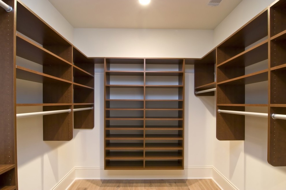 This is an example of a mid-sized transitional gender-neutral walk-in wardrobe in Boston with open cabinets, dark wood cabinets, light hardwood floors and beige floor.