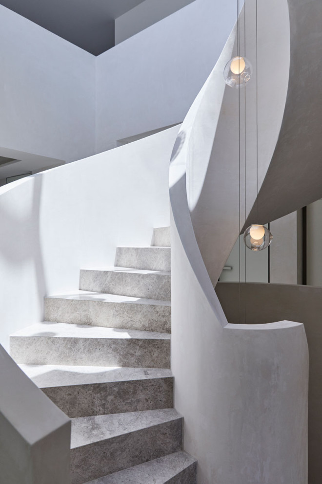 Réalisation d'un très grand escalier hélicoïdal minimaliste avec des marches en pierre calcaire et des contremarches en pierre calcaire.