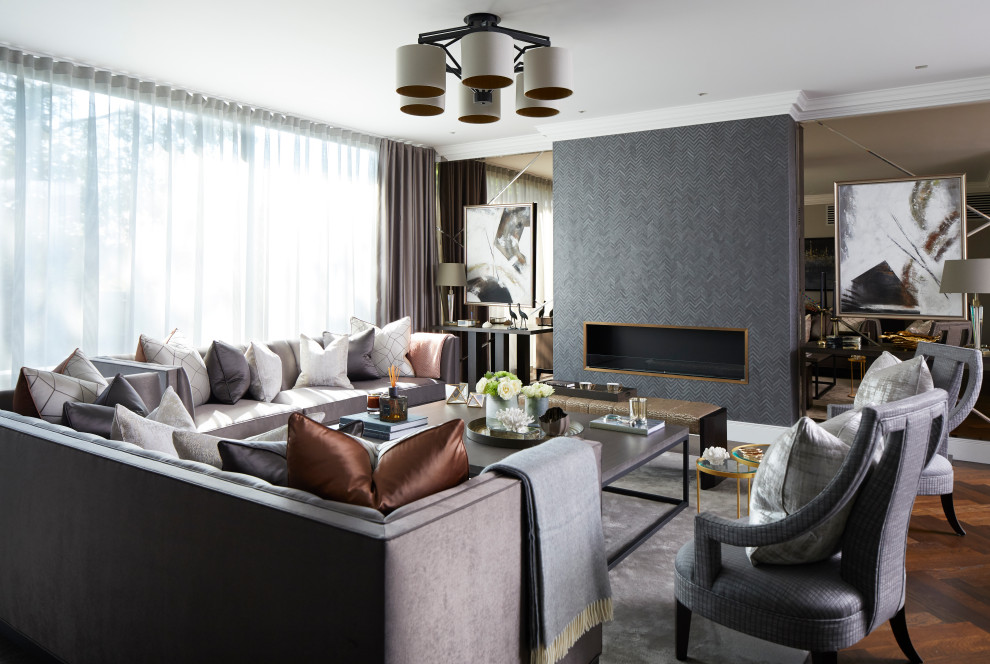 This is an example of a large transitional formal enclosed living room in London with grey walls, a hanging fireplace, a metal fireplace surround, black floor, medium hardwood floors and no tv.