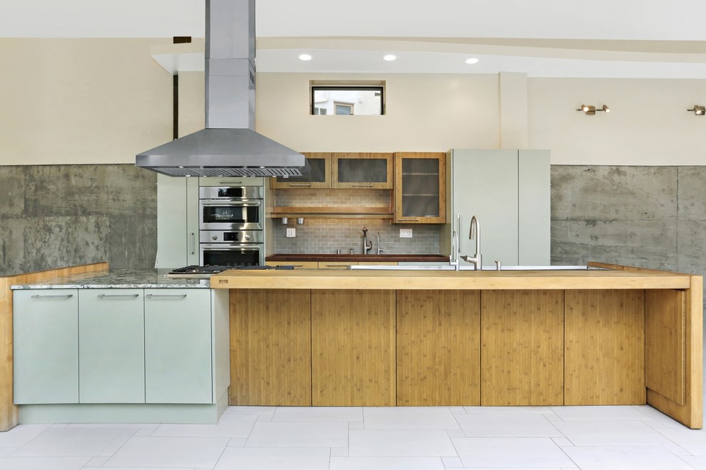 Inspiration for a mid-sized modern galley open plan kitchen in Los Angeles with an integrated sink, flat-panel cabinets, light wood cabinets, granite benchtops, beige splashback, porcelain splashback, stainless steel appliances, porcelain floors, with island and grey floor.