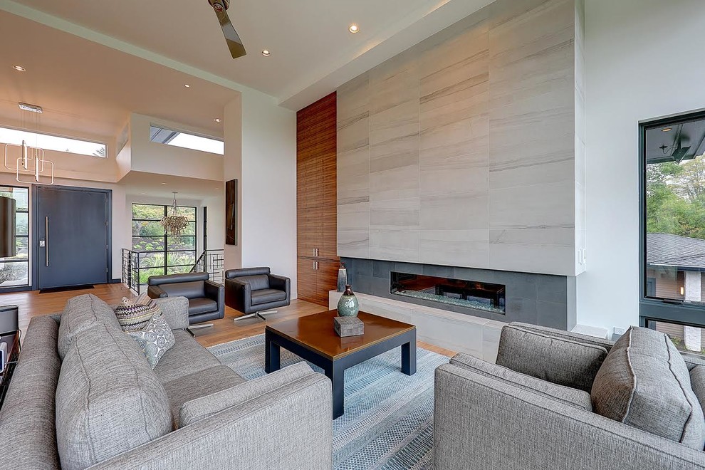 Large contemporary formal open concept living room in Portland with a ribbon fireplace, no tv, white walls, light hardwood floors and a tile fireplace surround.