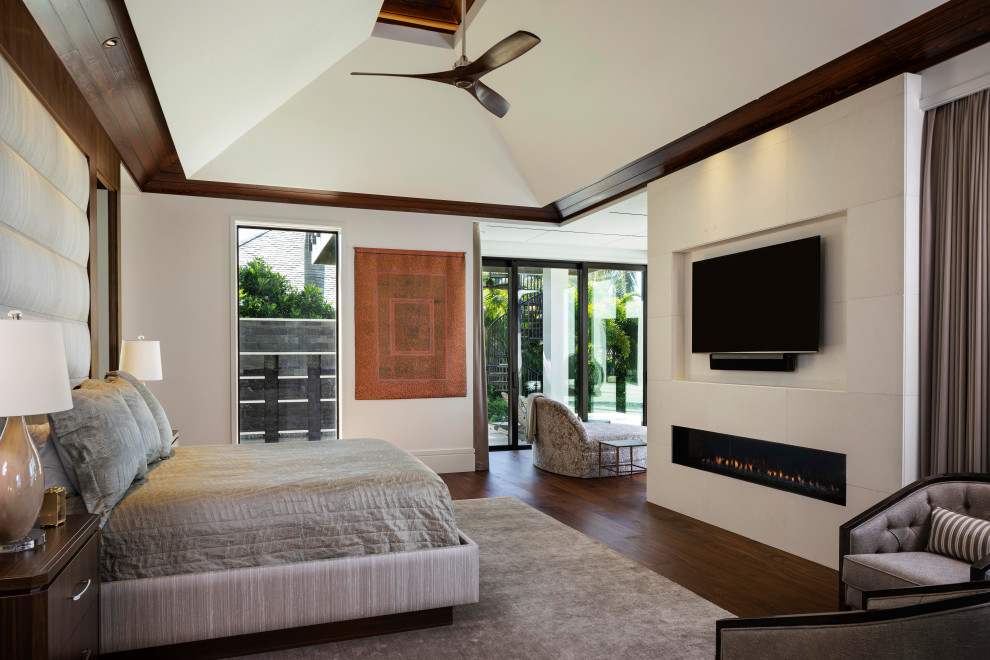 Photo of a large mediterranean master bedroom with white walls, medium hardwood floors, a standard fireplace, a tile fireplace surround, vaulted and wood walls.