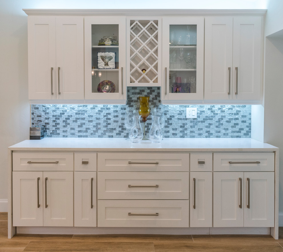 Transitional kitchen in Miami with an undermount sink, shaker cabinets, white cabinets, quartz benchtops, grey splashback, subway tile splashback, stainless steel appliances, with island and white benchtop.