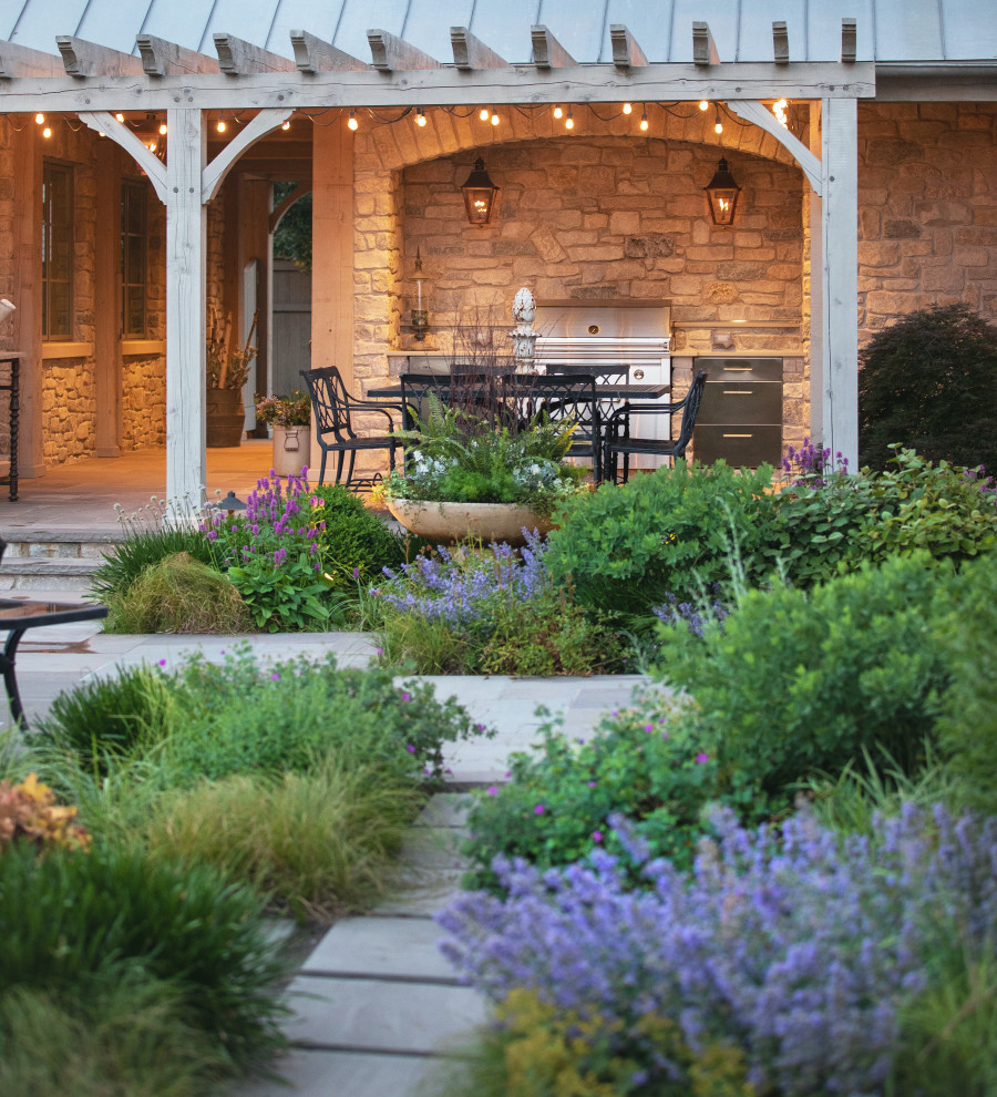 Immagine di un grande giardino chic esposto in pieno sole dietro casa in estate con un focolare, pavimentazioni in pietra naturale e recinzione in legno