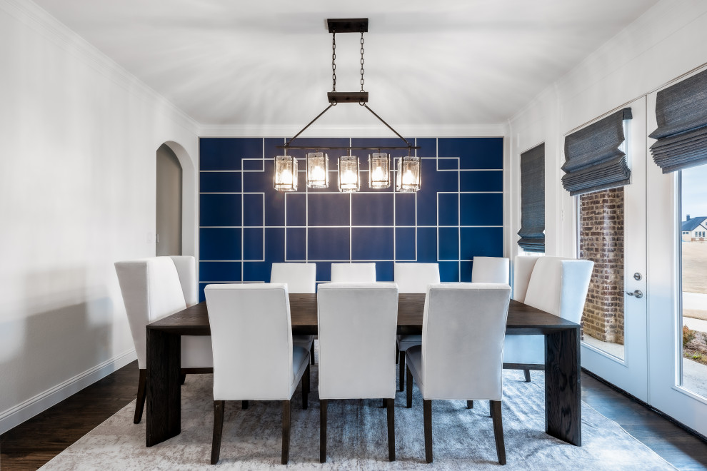 Cette image montre une grande salle à manger ouverte sur la cuisine traditionnelle avec un mur bleu, parquet foncé, un sol marron et boiseries.