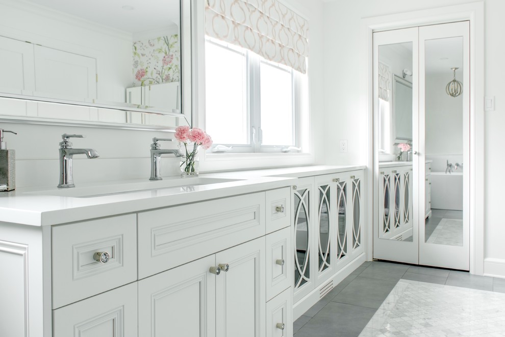 Inspiration for a large transitional master bathroom in Montreal with glass-front cabinets, white cabinets, a freestanding tub, white walls, porcelain floors, an undermount sink, engineered quartz benchtops, grey floor and white benchtops.