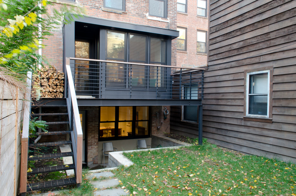 Large modern brick brown townhouse exterior in New York with a flat roof and four or more storeys.