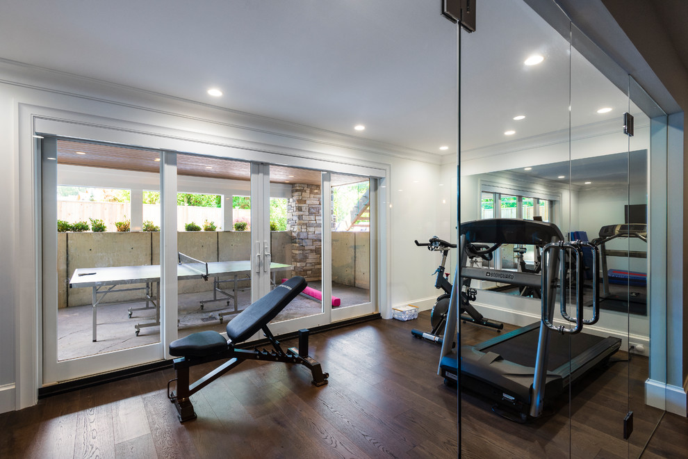 This is an example of a mid-sized country home weight room in Vancouver with white walls, medium hardwood floors and brown floor.