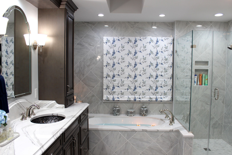 This is an example of a large transitional master bathroom in Baltimore with raised-panel cabinets, grey cabinets, an undermount tub, a two-piece toilet, white tile, porcelain tile, grey walls, porcelain floors, an undermount sink, engineered quartz benchtops, white floor, a hinged shower door, white benchtops, a shower seat, a double vanity, a built-in vanity and vaulted.
