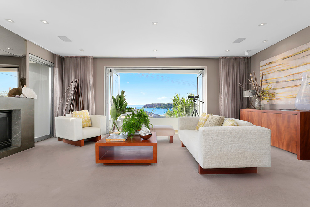 This is an example of a contemporary living room in Sydney with grey walls, carpet, a standard fireplace and grey floor.