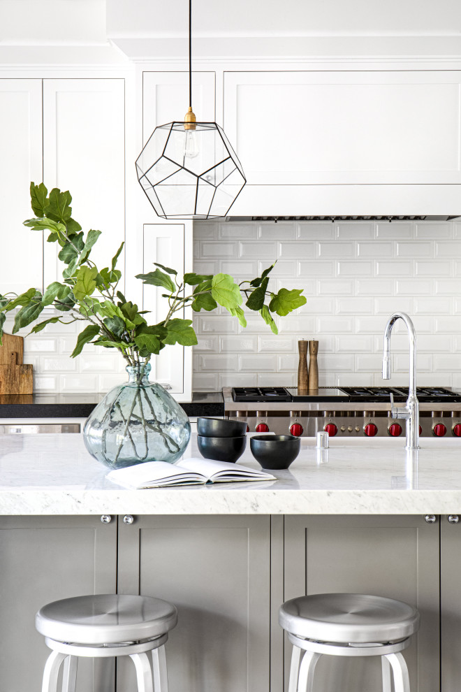 Example of a large transitional master and l-shaped light wood floor, brown floor, vaulted ceiling and wallpaper open concept kitchen design in Orange County with gray walls, a farmhouse sink, shaker cabinets, white cabinets, marble countertops, white backsplash, subway tile backsplash, stainless steel appliances, an island and white countertops