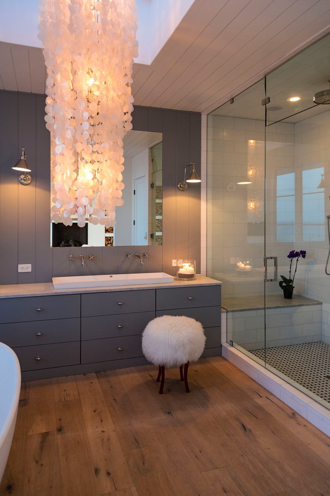 Inspiration for a large transitional master white tile and subway tile medium tone wood floor alcove shower remodel with flat-panel cabinets, gray cabinets, white walls, a trough sink and quartz countertops
