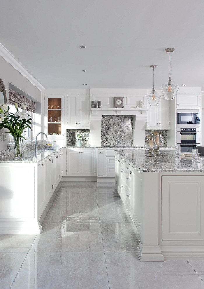 Photo of a large transitional l-shaped eat-in kitchen in Other with an undermount sink, beaded inset cabinets, white cabinets, granite benchtops, grey splashback, stone slab splashback, stainless steel appliances, porcelain floors, with island and grey floor.