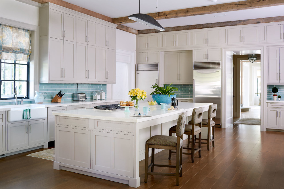 Inspiration for a traditional kitchen in Other with a farmhouse sink, shaker cabinets, blue splashback, subway tile splashback, stainless steel appliances, medium hardwood floors, with island, white benchtop and beige cabinets.