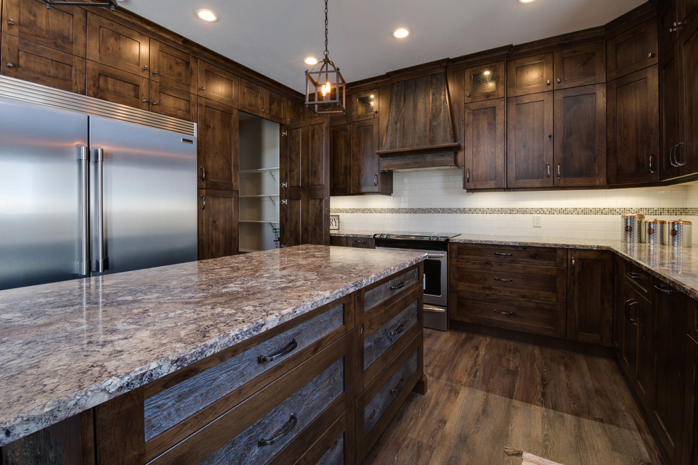 Eat-in kitchen - large rustic u-shaped eat-in kitchen idea with an undermount sink, shaker cabinets, dark wood cabinets, laminate countertops, subway tile backsplash, stainless steel appliances, an island and brown countertops