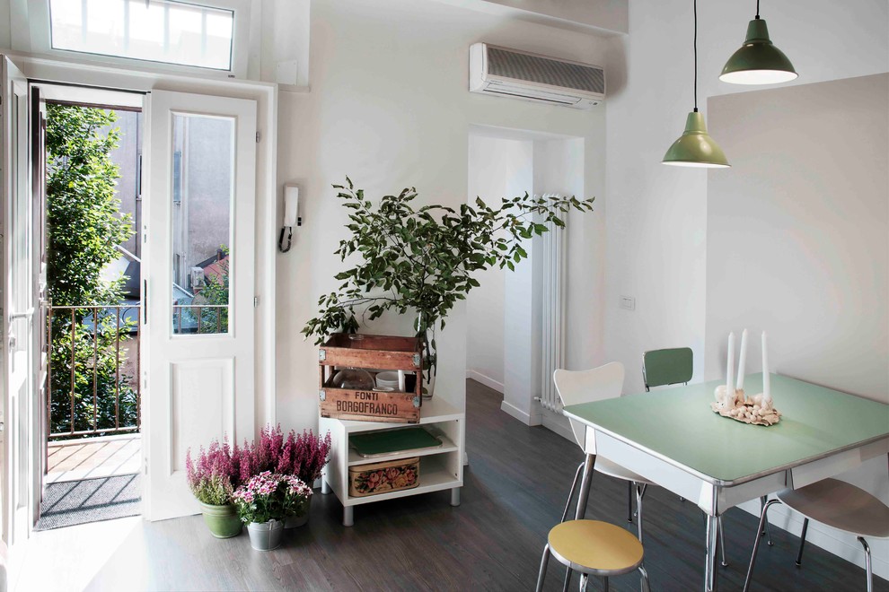 Inspiration for an eclectic dining room in Milan with white walls and dark hardwood floors.