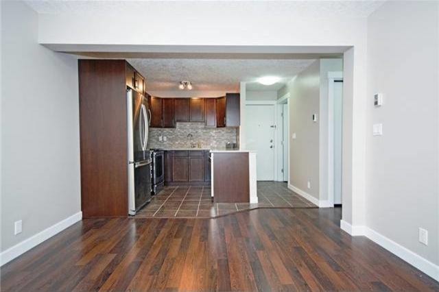 Kitchen - small transitional u-shaped ceramic tile and brown floor kitchen idea in Calgary with an undermount sink, recessed-panel cabinets, dark wood cabinets, multicolored backsplash, matchstick tile backsplash and stainless steel appliances