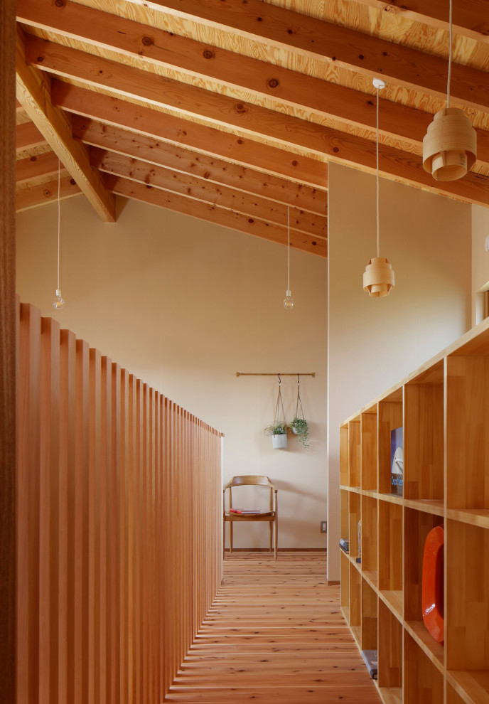 Wohnzimmer mit beiger Wandfarbe, braunem Holzboden, freigelegten Dachbalken und Tapetenwänden in Sonstige