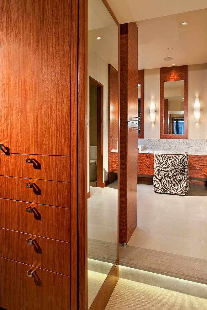 Photo of a mid-sized contemporary gender-neutral walk-in wardrobe in Denver with flat-panel cabinets, medium wood cabinets, carpet and white floor.