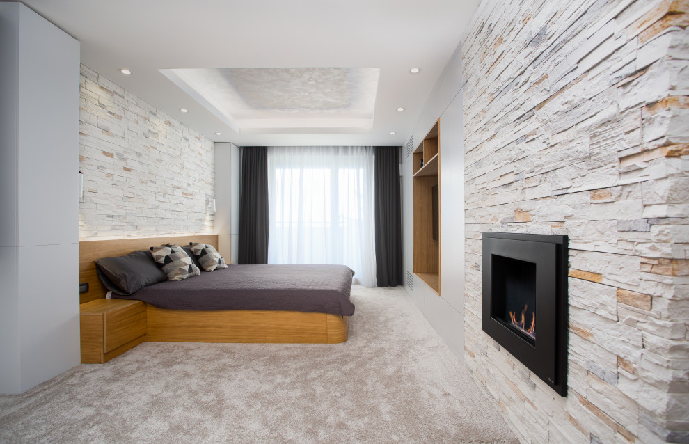 Großes Modernes Hauptschlafzimmer mit Teppichboden, Kamin, Kaminumrandung aus Stein, grauem Boden und eingelassener Decke in Sonstige