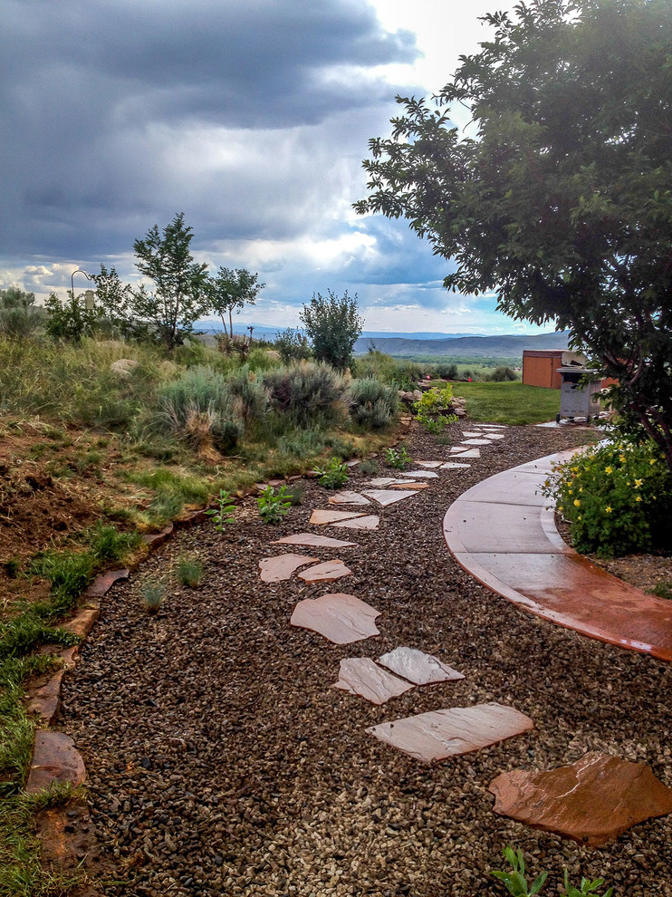 This is an example of a large country partial sun garden in Denver with a garden path and natural stone pavers.