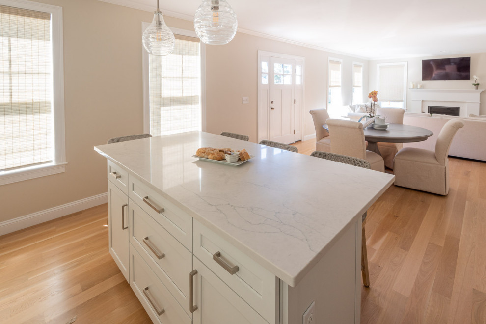 Open concept kitchen - huge transitional l-shaped light wood floor and brown floor open concept kitchen idea in Boston with an undermount sink, shaker cabinets, white cabinets, quartz countertops, gray backsplash, subway tile backsplash, stainless steel appliances, an island and white countertops