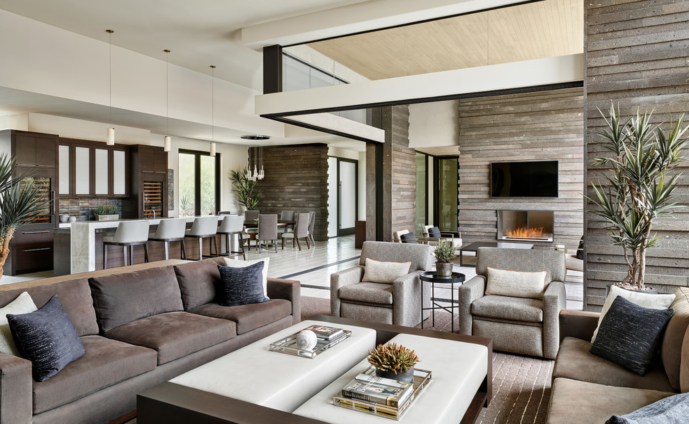 Large trendy open concept white floor family room photo in Phoenix with a bar, brown walls, a two-sided fireplace, a stone fireplace and a wall-mounted tv