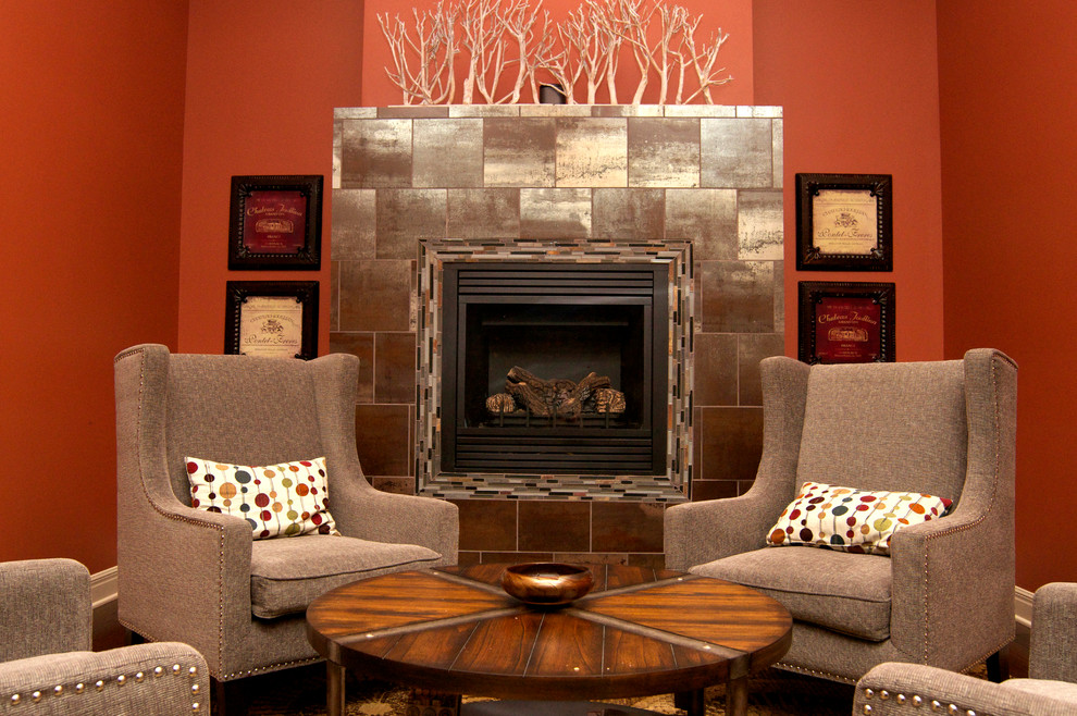 Mid-sized modern fully buried basement in Kansas City with orange walls, dark hardwood floors, a standard fireplace, a metal fireplace surround and brown floor.