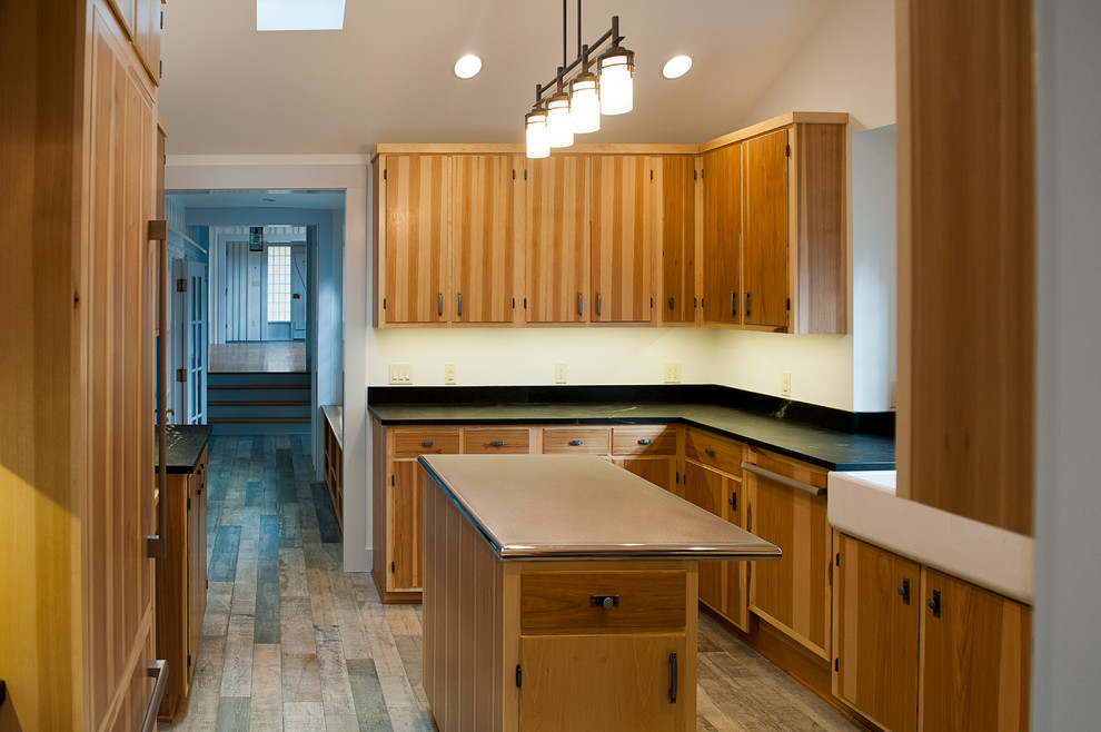 Example of a large mountain style u-shaped enclosed kitchen design with a farmhouse sink, flat-panel cabinets, medium tone wood cabinets, soapstone countertops, stainless steel appliances and an island