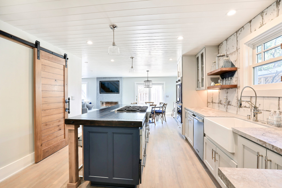Bild på ett mellanstort eklektiskt grå grått kök, med en rustik diskho, skåp i shakerstil, bänkskiva i kvarts, vitt stänkskydd, stänkskydd i porslinskakel, färgglada vitvaror, ljust trägolv och en köksö