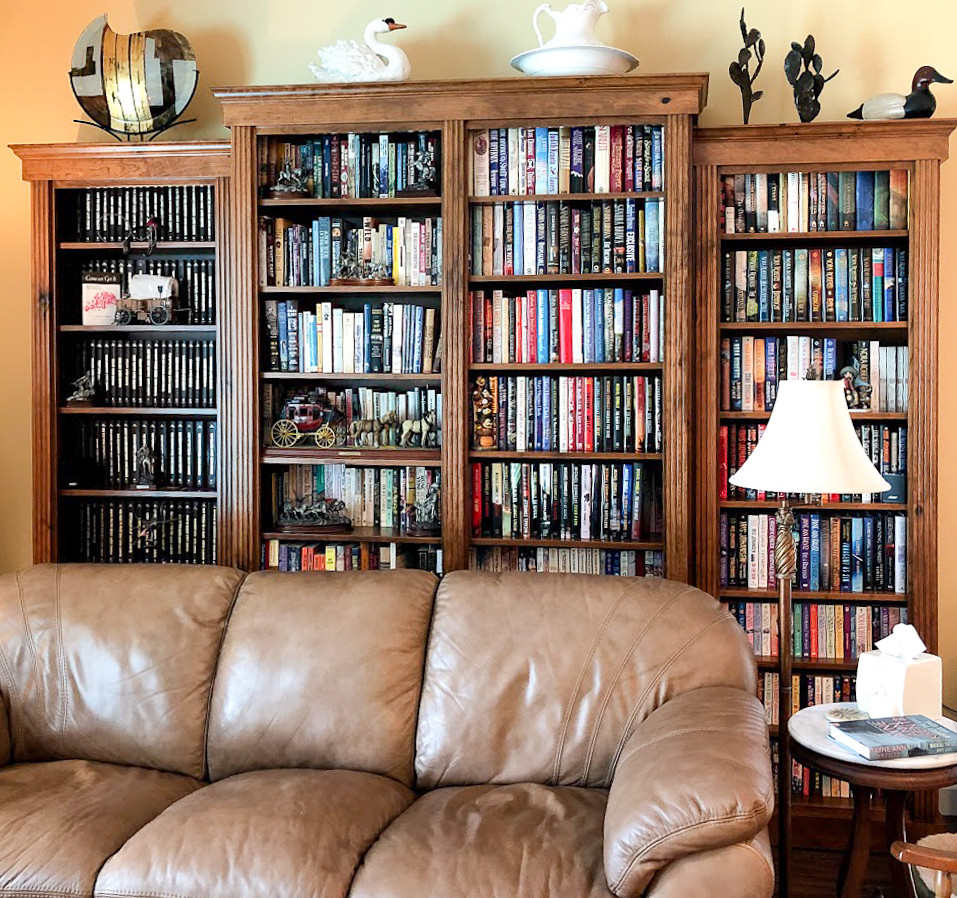 Esempio di un soggiorno chic di medie dimensioni e aperto con libreria e pareti gialle