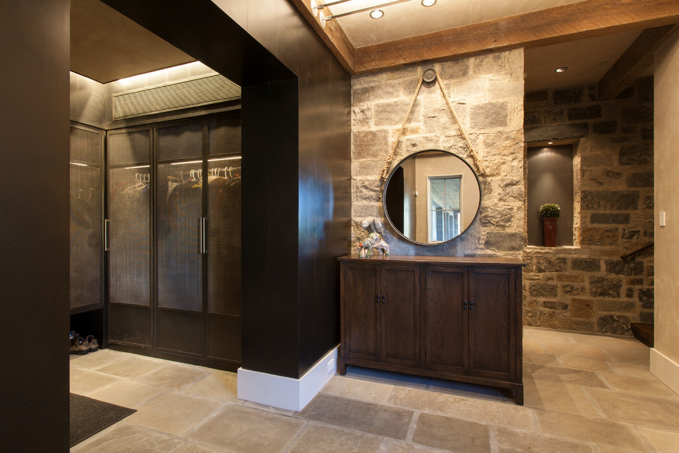 This is an example of a country gender-neutral storage and wardrobe in Denver with travertine floors, recessed-panel cabinets and dark wood cabinets.