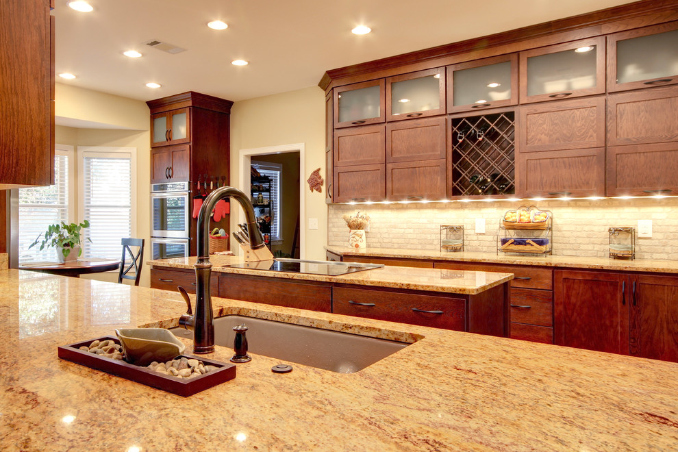 Transitional eat-in kitchen photo in Miami with an undermount sink, shaker cabinets, brown cabinets, granite countertops, beige backsplash, stone tile backsplash and stainless steel appliances