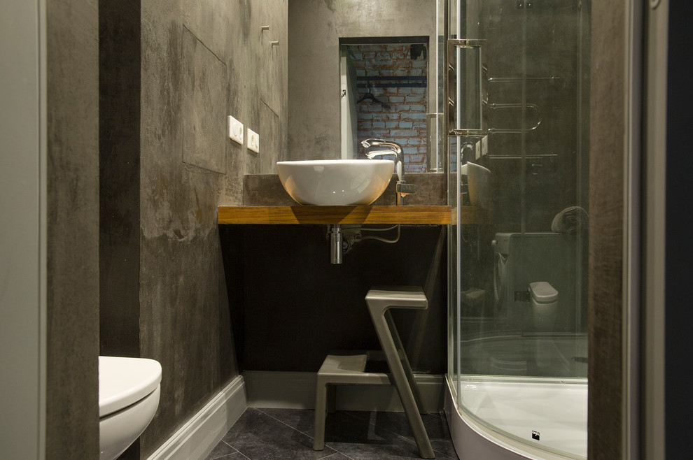 Photo of an industrial bathroom in Moscow with a corner shower, a vessel sink and wood benchtops.