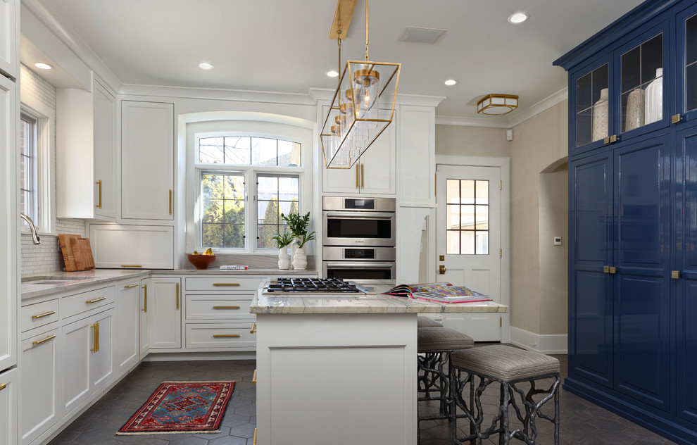 Large transitional u-shaped porcelain tile and gray floor enclosed kitchen photo in Milwaukee with an undermount sink, shaker cabinets, white cabinets, marble countertops, white backsplash, mosaic tile backsplash, stainless steel appliances, an island and multicolored countertops