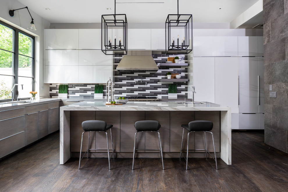 Mid-sized contemporary l-shaped open plan kitchen in Houston with an undermount sink, flat-panel cabinets, white cabinets, multi-coloured splashback, stainless steel appliances, dark hardwood floors, with island, brown floor, white benchtop, marble benchtops and glass tile splashback.