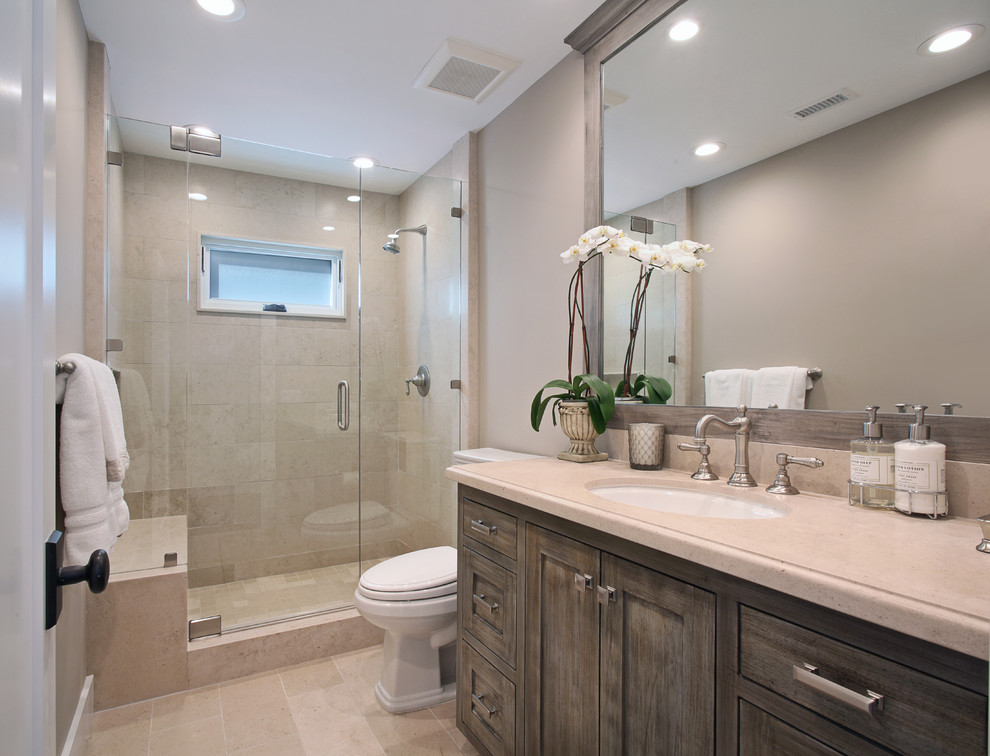 Design ideas for a mid-sized traditional kids bathroom in Orange County with dark wood cabinets, beige tile, marble floors, recessed-panel cabinets, an alcove shower, a two-piece toilet, porcelain tile, grey walls, an undermount sink, limestone benchtops, beige floor, a hinged shower door and beige benchtops.