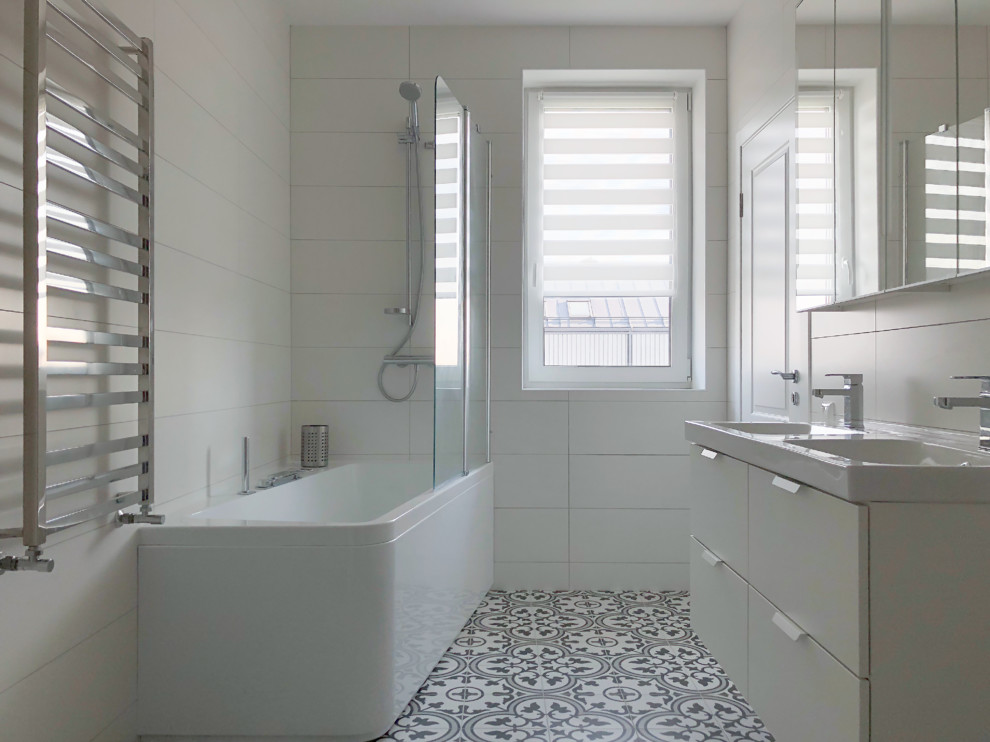 Small scandinavian master bathroom in Stockholm with white walls, ceramic floors, a corner tub, a shower/bathtub combo, an open shower, flat-panel cabinets, white cabinets, white tile, a console sink and multi-coloured floor.