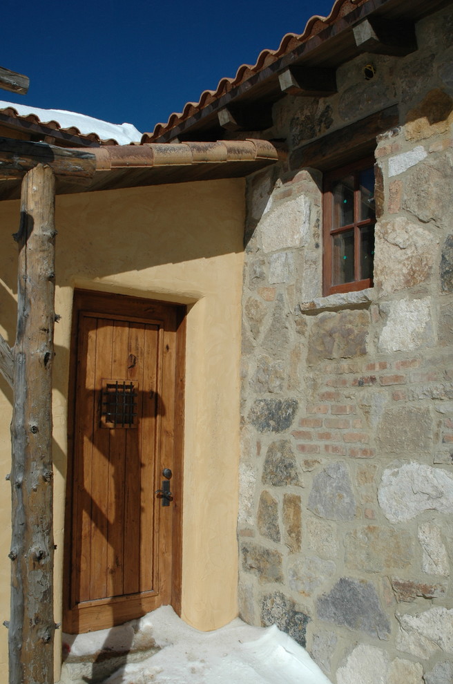 This is an example of a large traditional three-storey beige exterior in Denver with stone veneer and a hip roof.