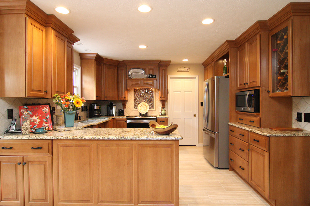 Example of a large transitional u-shaped porcelain tile eat-in kitchen design with raised-panel cabinets, medium tone wood cabinets, granite countertops, beige backsplash, porcelain backsplash and stainless steel appliances