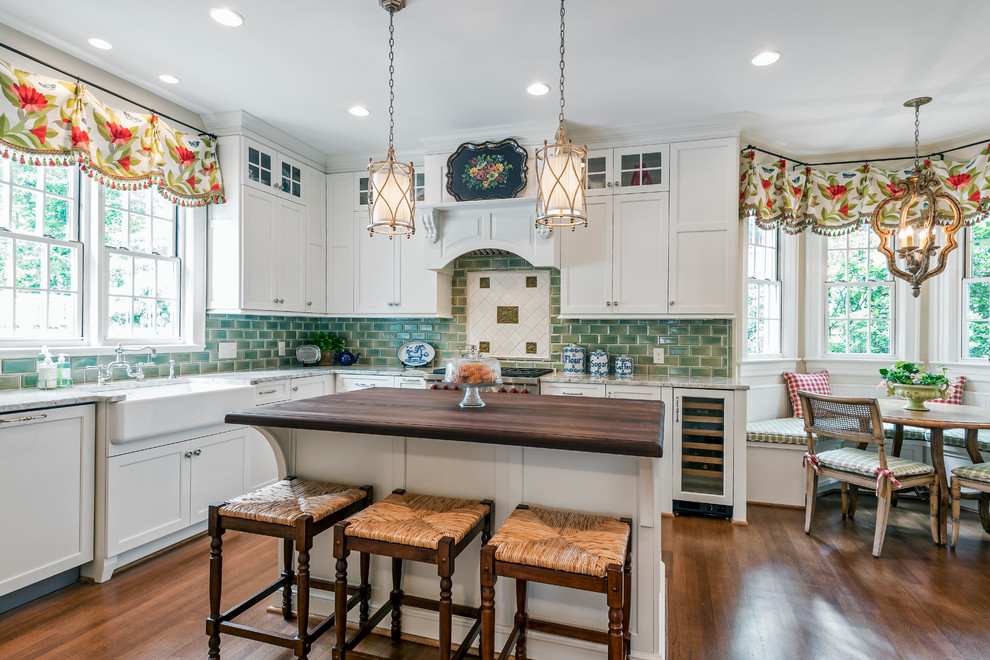 Example of a large transitional l-shaped light wood floor eat-in kitchen design with a farmhouse sink, shaker cabinets, white cabinets, marble countertops, green backsplash, ceramic backsplash, stainless steel appliances and an island