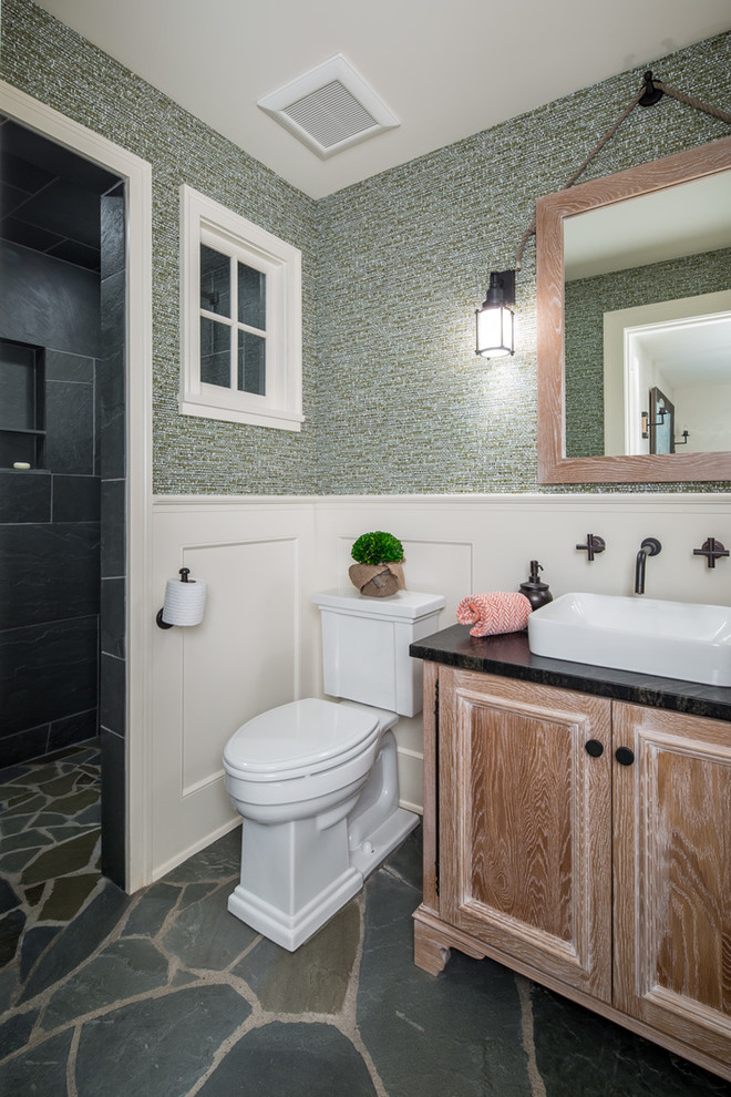 Inspiration for an arts and crafts bathroom in Minneapolis with recessed-panel cabinets, medium wood cabinets, a curbless shower, green walls, a vessel sink, grey floor, an open shower and black benchtops.