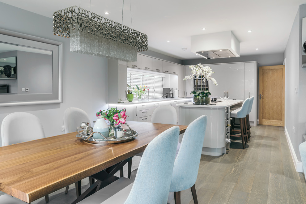 Inspiration for a mid-sized contemporary u-shaped open plan kitchen in Essex with an integrated sink, flat-panel cabinets, grey cabinets, window splashback, panelled appliances, vinyl floors, with island, brown floor and white benchtop.