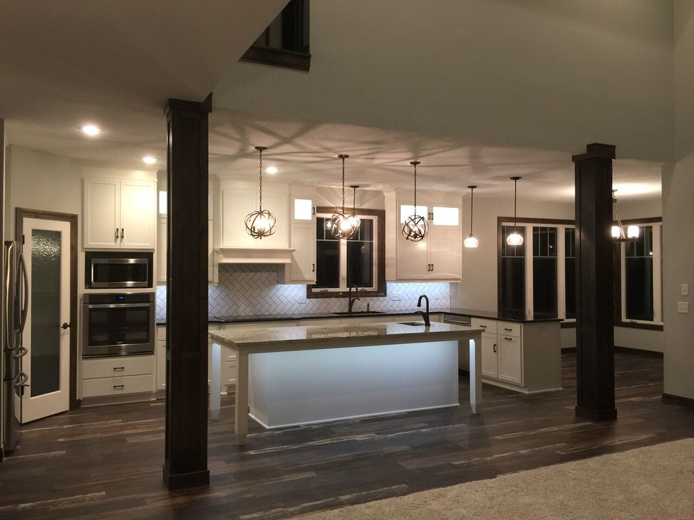 Inspiration for a mid-sized transitional laminate floor kitchen remodel in Minneapolis with white cabinets, subway tile backsplash and stainless steel appliances