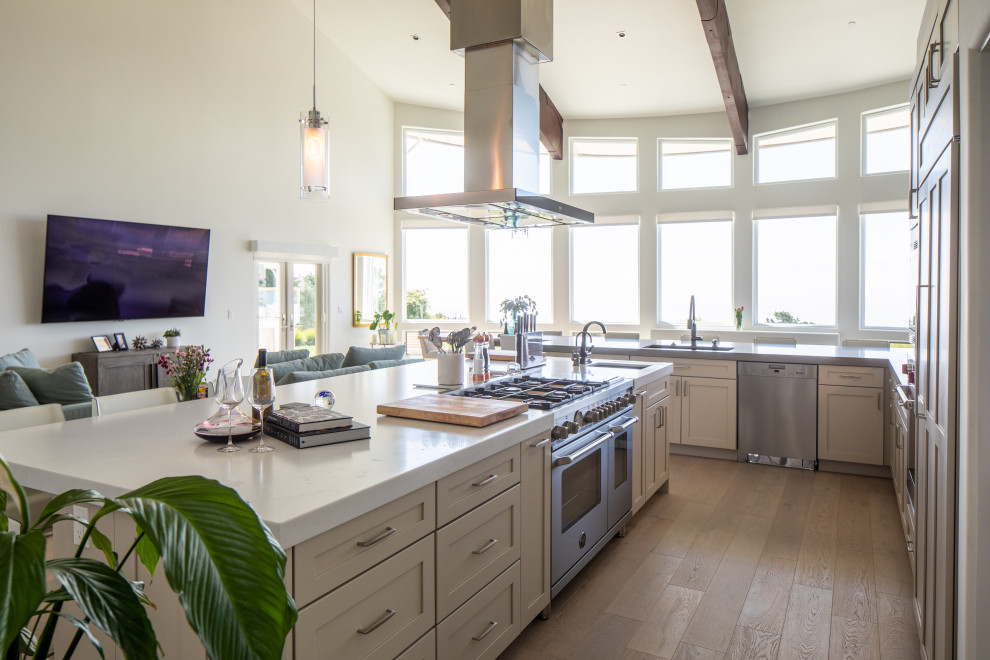 Example of a large transitional l-shaped light wood floor and white floor eat-in kitchen design with an undermount sink, shaker cabinets, gray cabinets, marble countertops, white backsplash, subway tile backsplash, stainless steel appliances, an island and white countertops